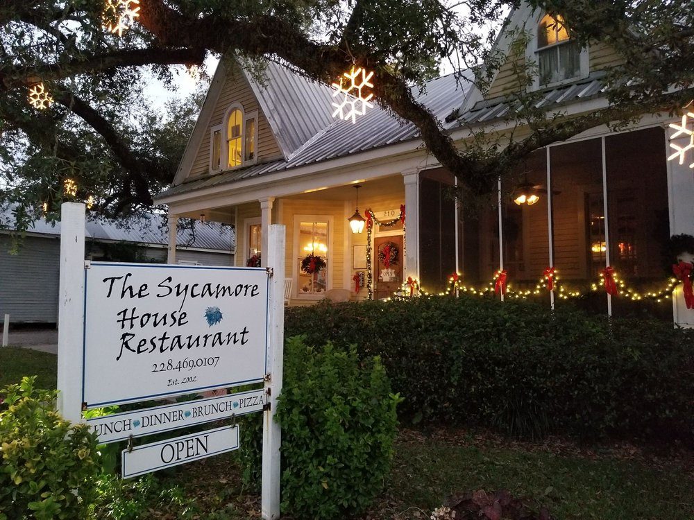 The Sycamore House lit up at night with its restaurant sign out front on Main Street